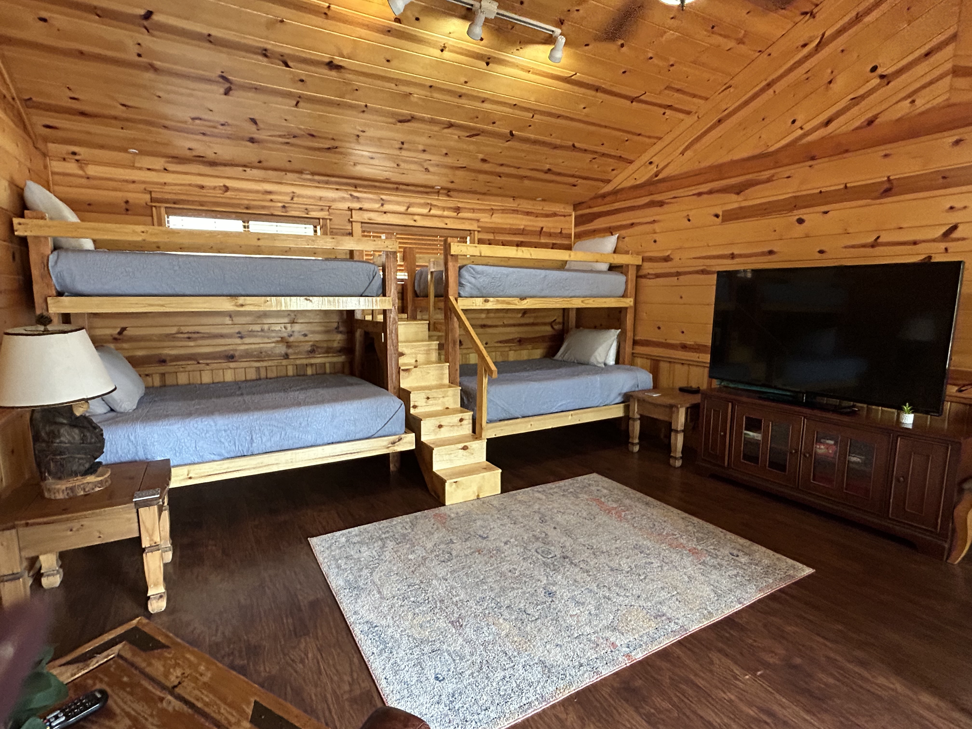 Front porch of a log cabin with a bright blue door and two black chairs.