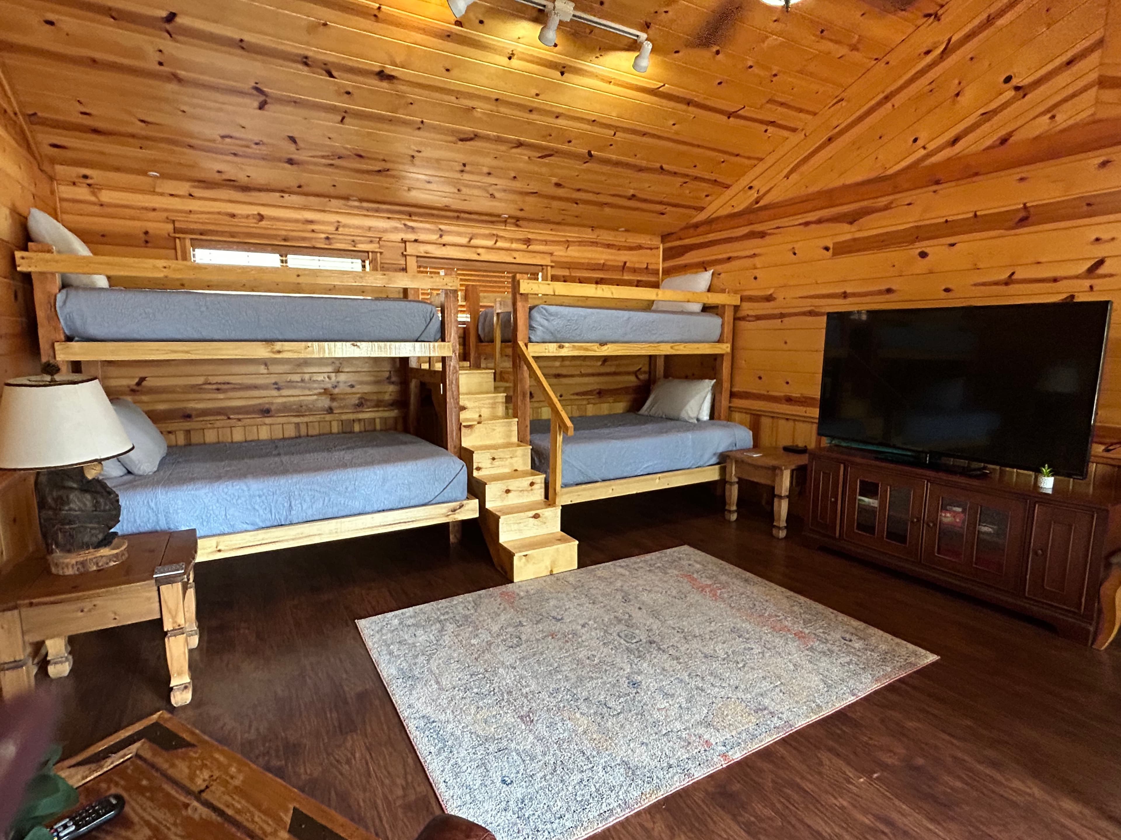 Front porch of a log cabin with a bright blue door and two black chairs.