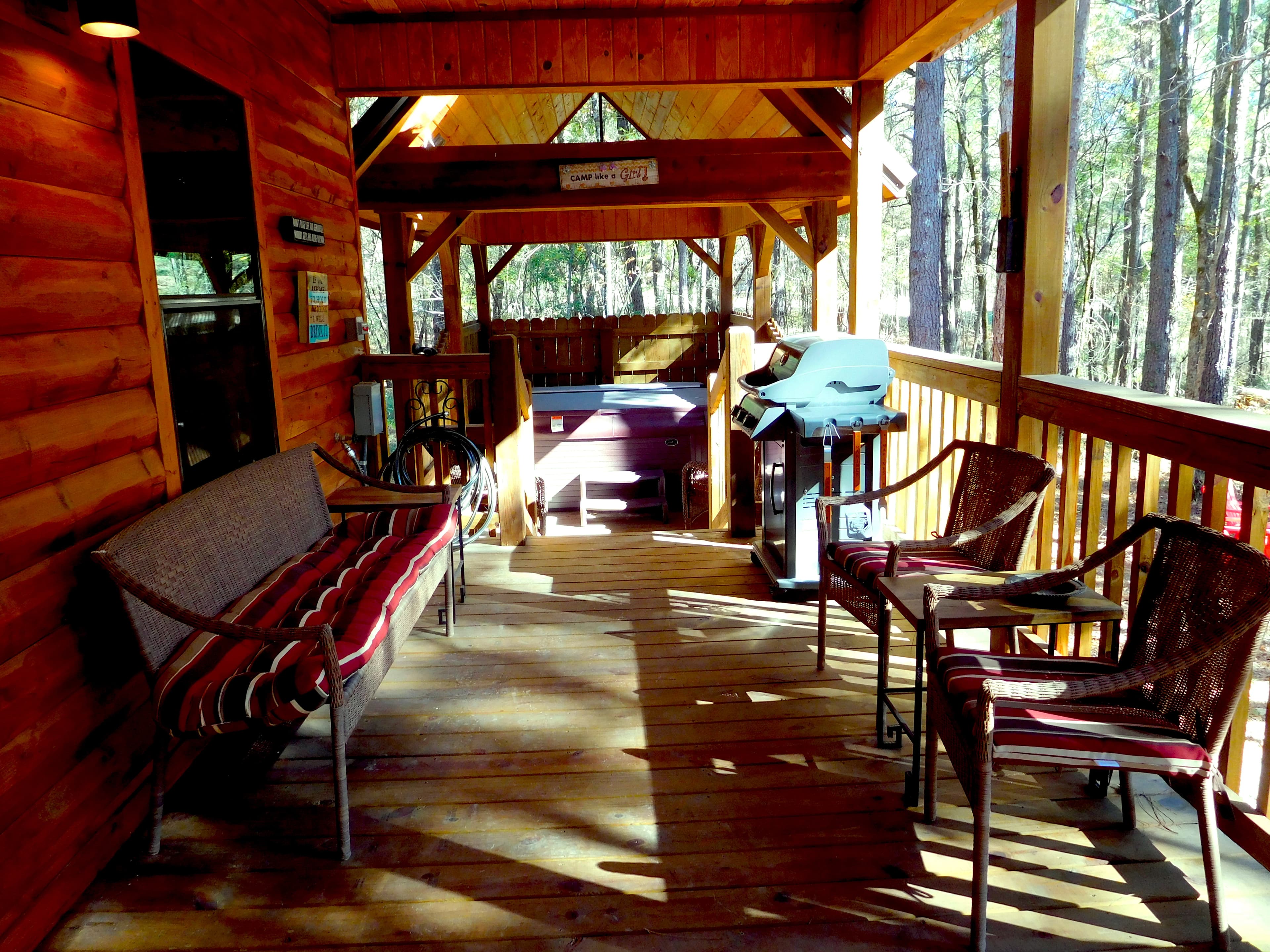 Covered porch with seating, hot tub, and grill