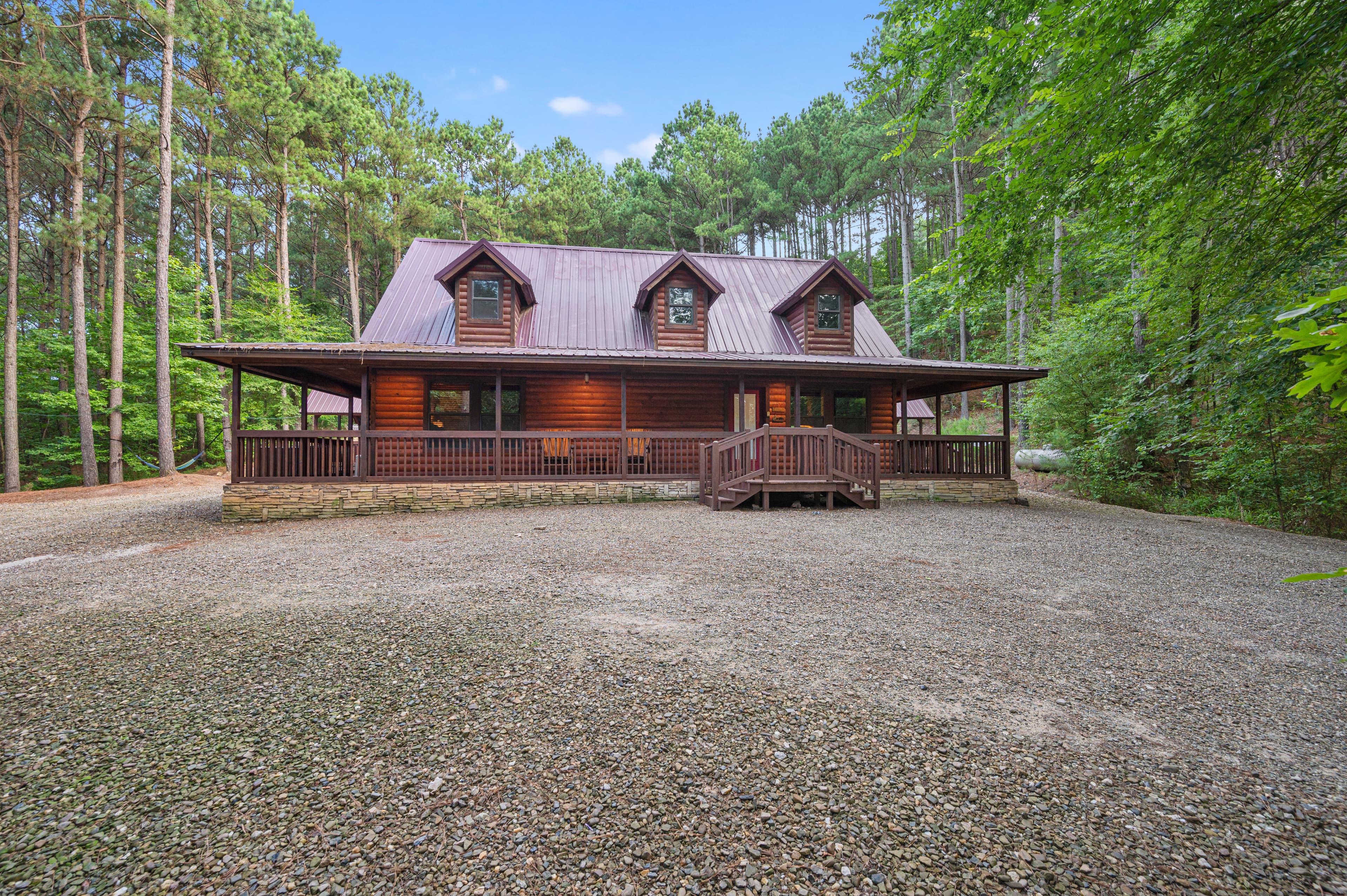 Front of log 2 story cabin with large driveway space