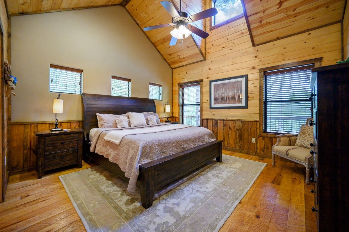King bedroom with side tables, lamps, a tv, and dresser