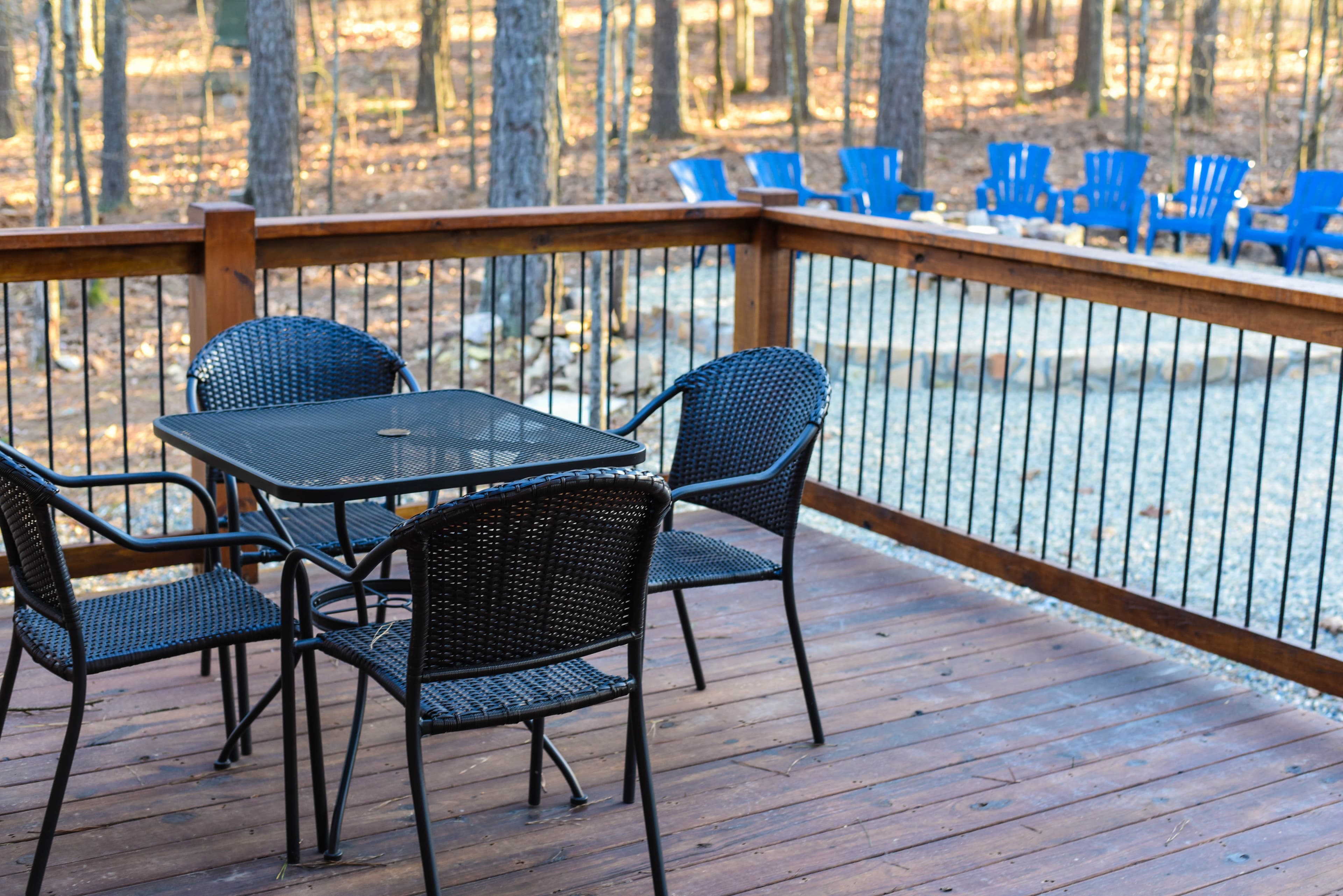 Table on back porch seating 4 with a fire-pit and forest view