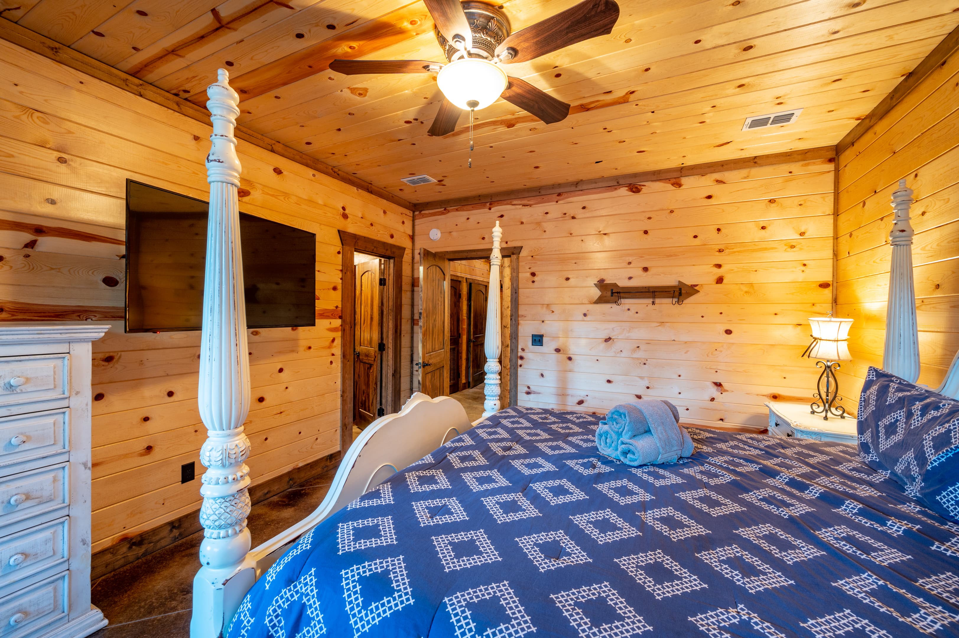 King bedroom with white dresser and large TV
