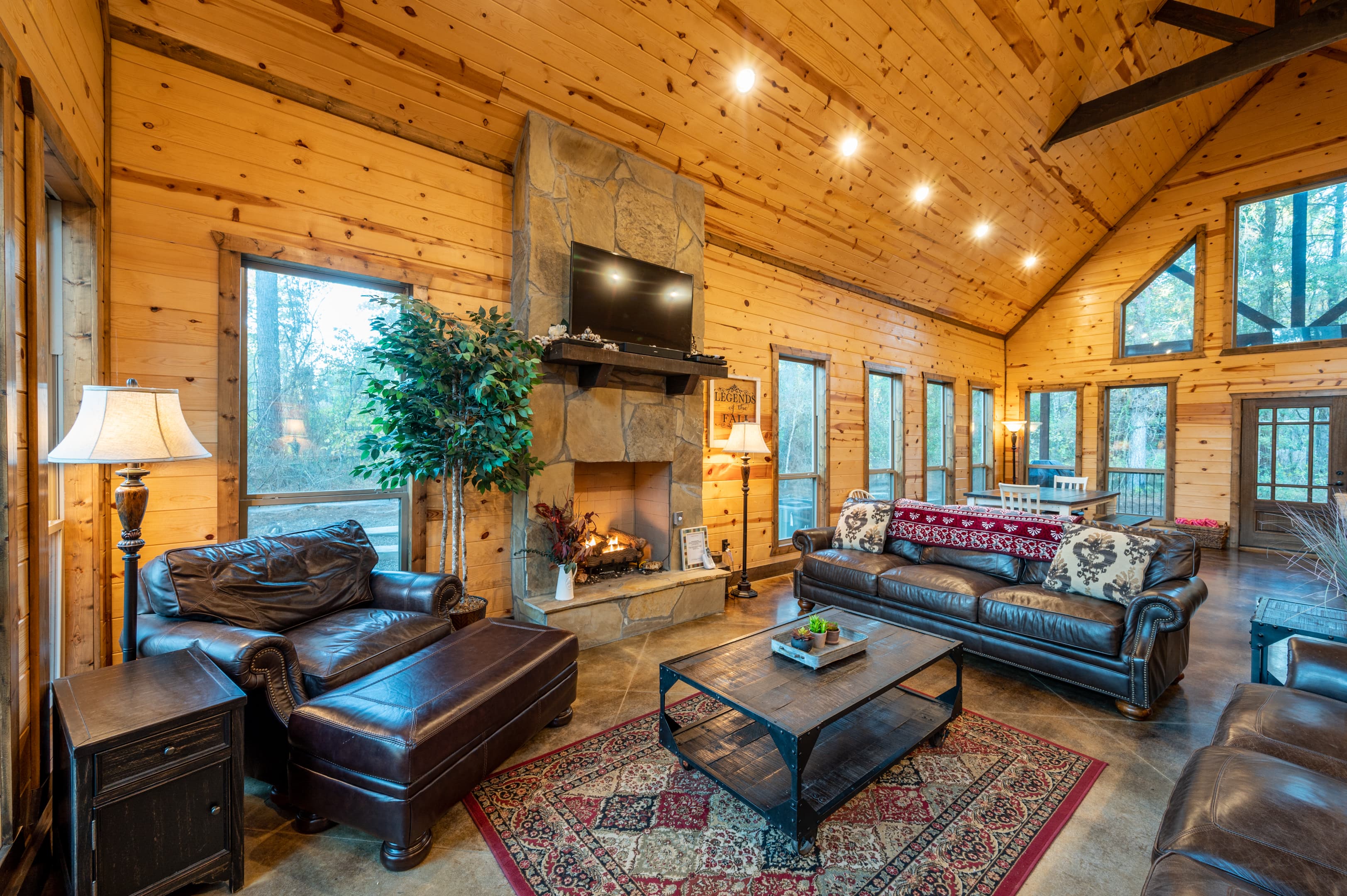 Living area with leather couches, rock fireplace, coffee table, and TV
