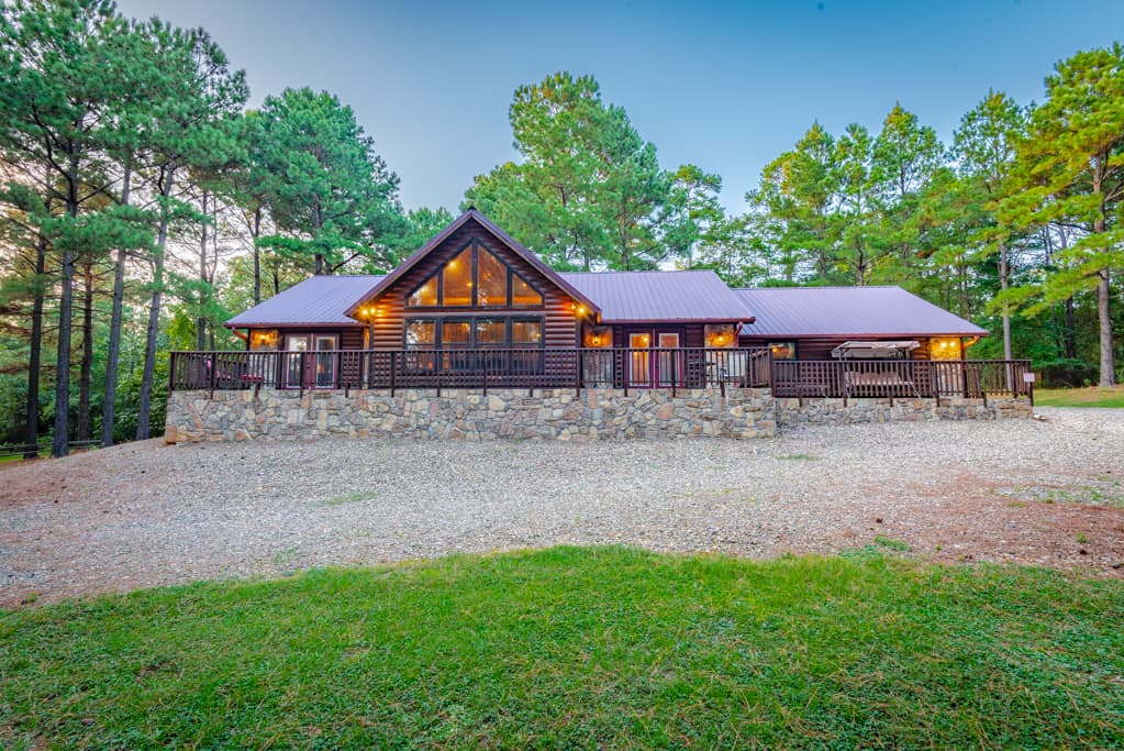 Front of log 1-story cabin with large driveway space