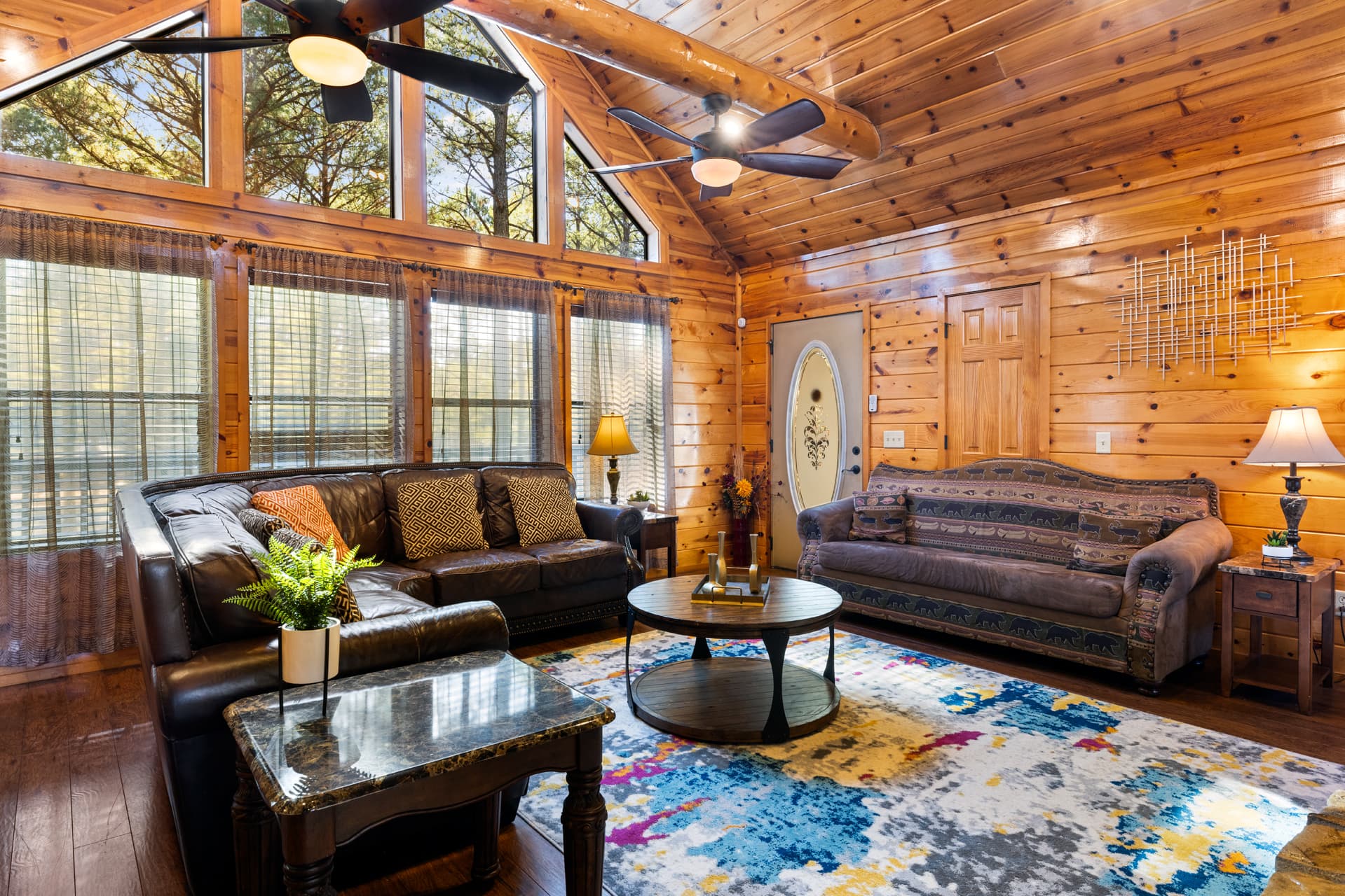 Living area with couches, side tables, and lamps, large abstract rug