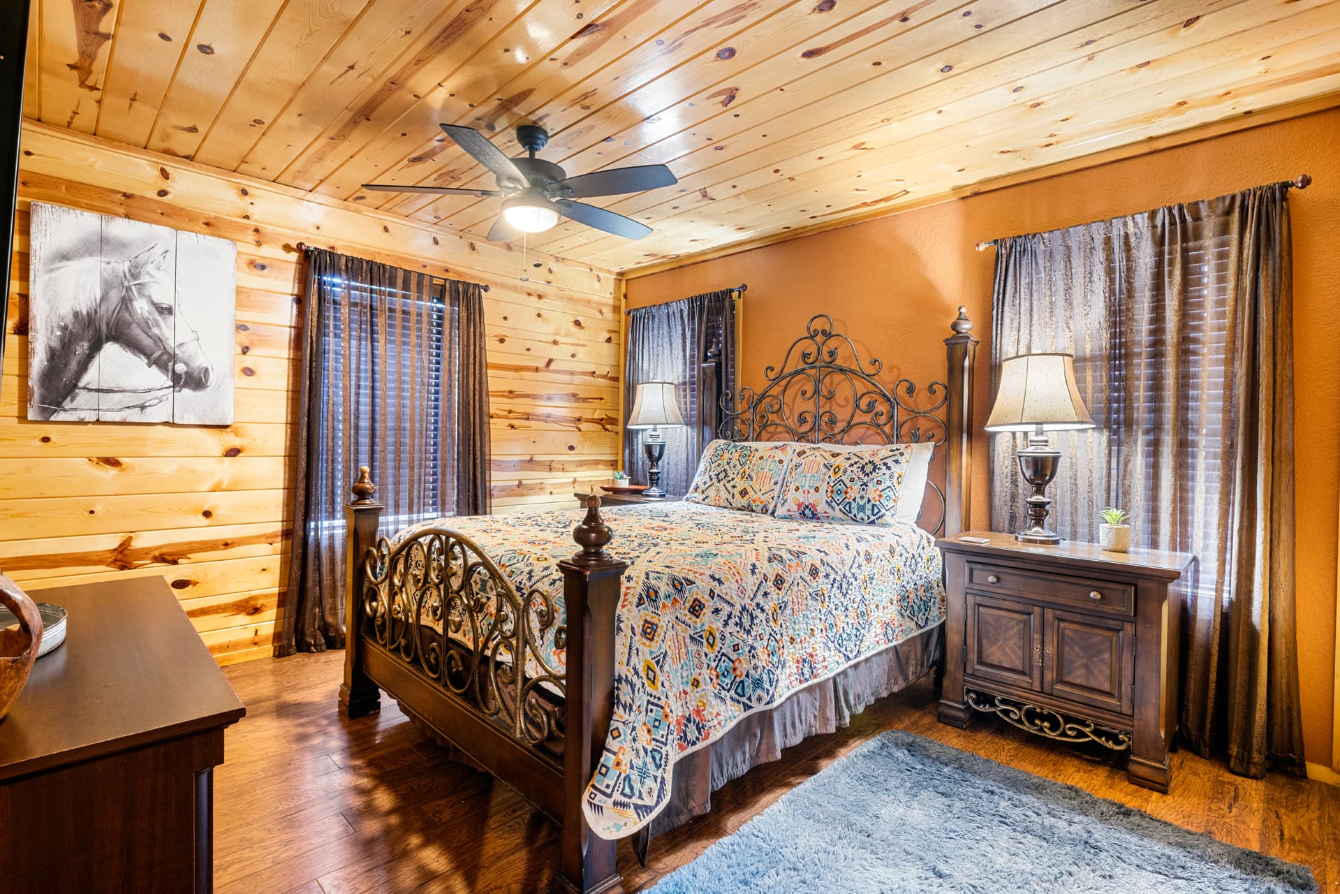 Queen back bedroom with side tables, a dresser and TV