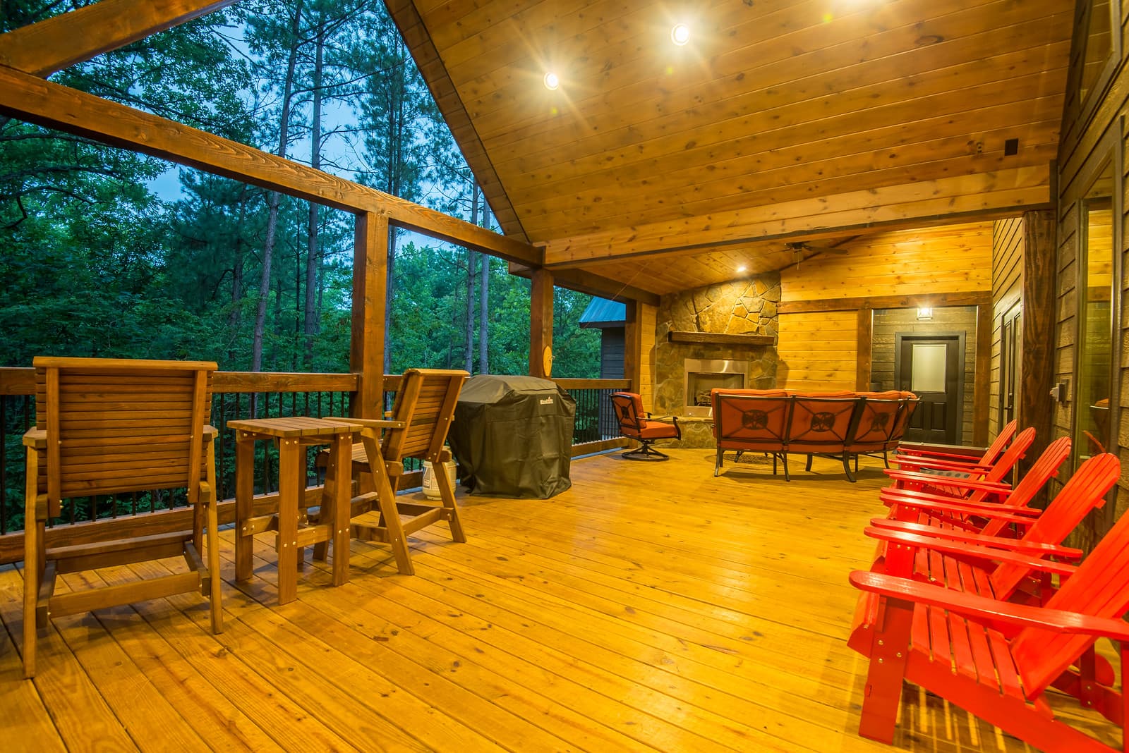 Covered back porch with a fireplace, grill, and seating with a forest view