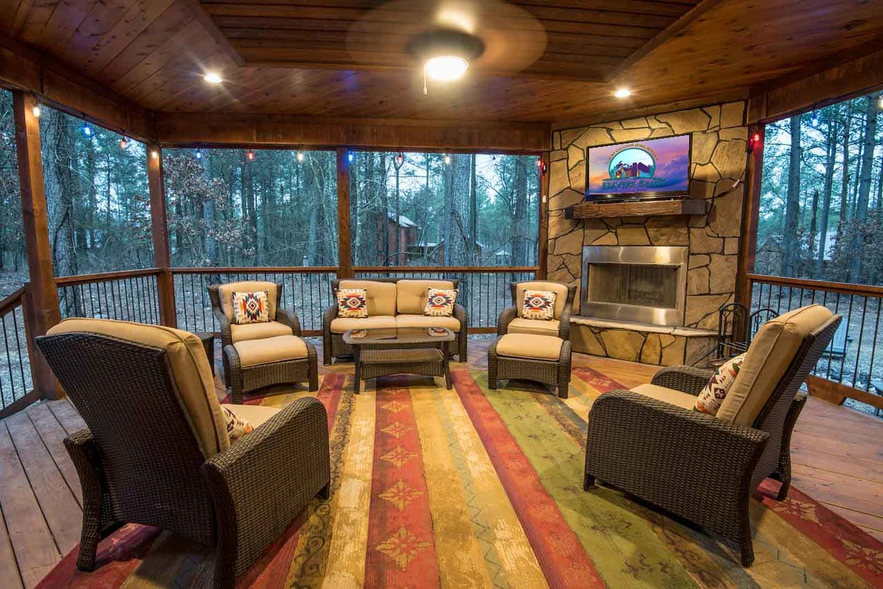 back porch with chairs, tv, fireplace, and forest view