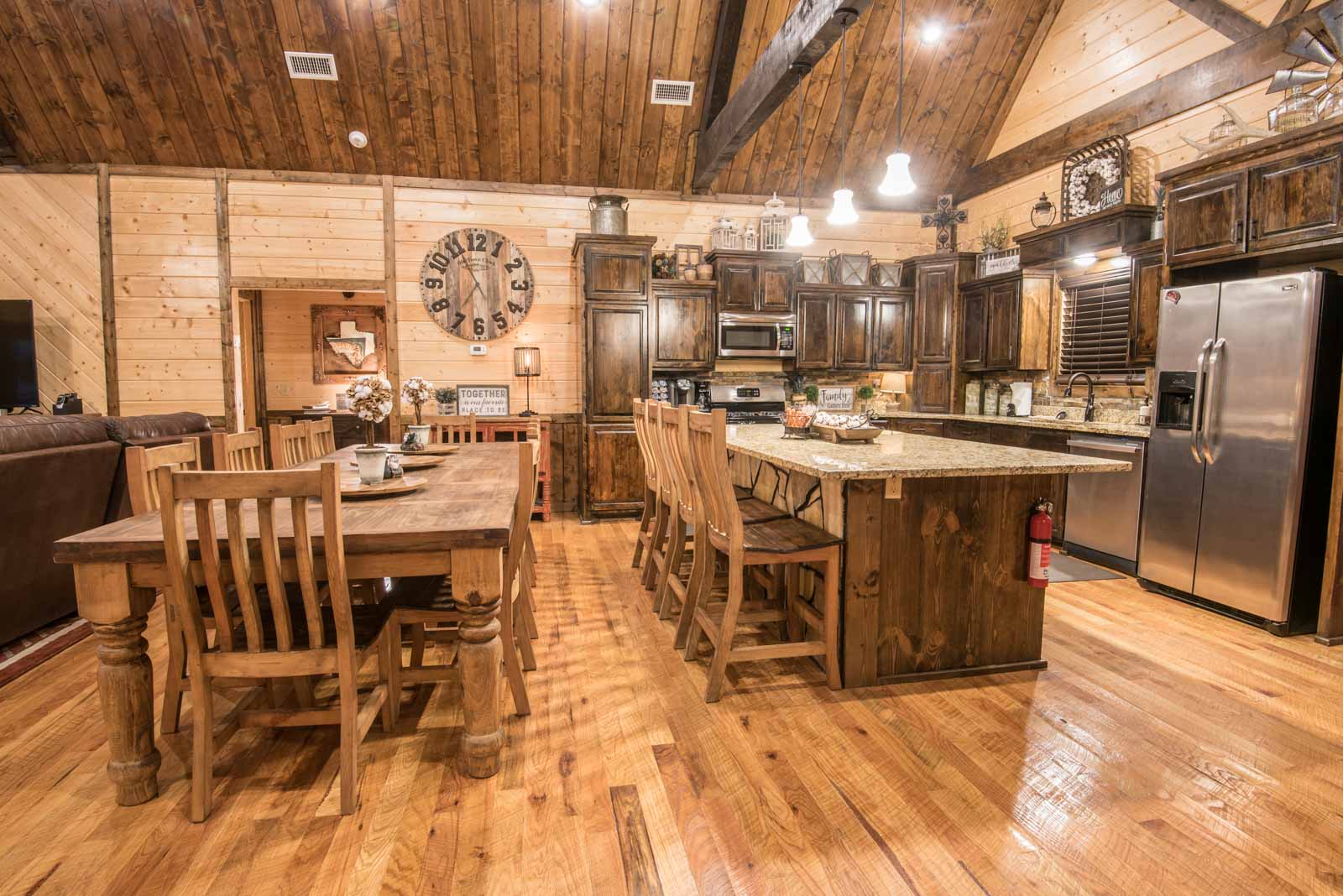 Open kitchen with stainless steel appliances, and an island with 4 chairs plus a kitchen table