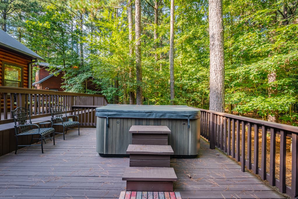 Hot tub on uncovered wooden patio with steps to get inside the tub with