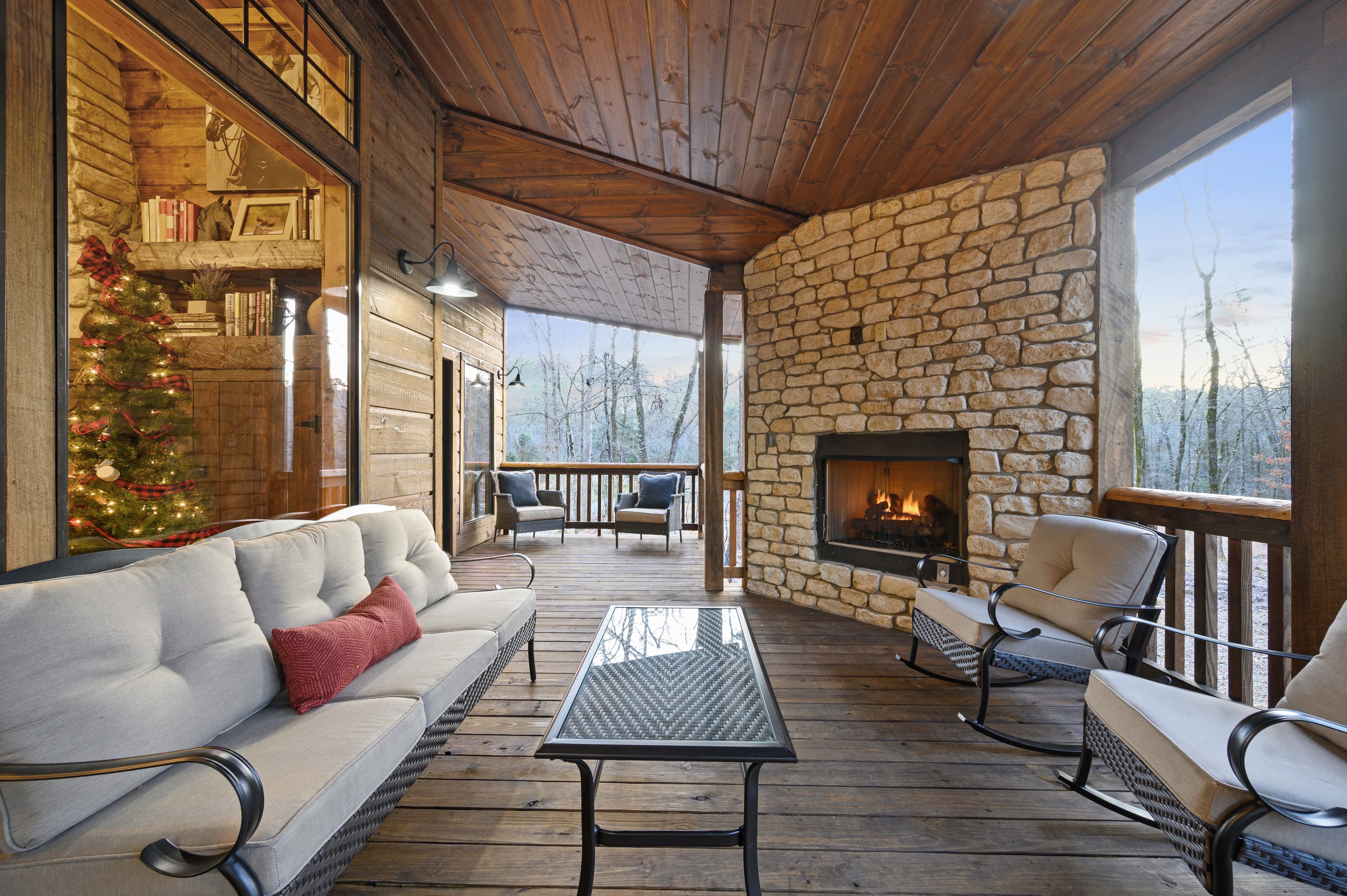 Back Porch With Outdoor Gas Fireplace, a Couch, Table, and Chairs with Forest View
