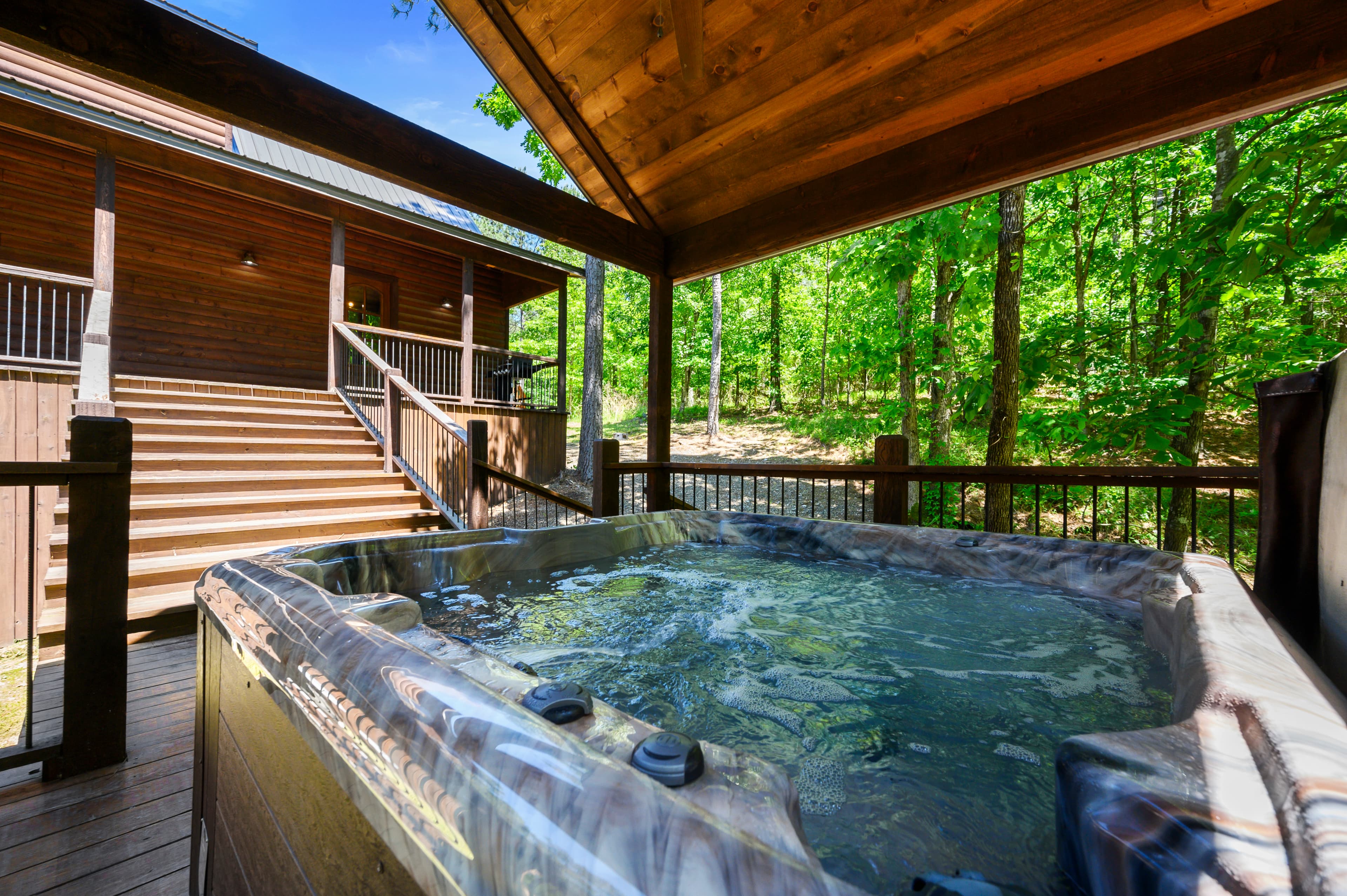 Hot tub on covered wooden porch with forest view