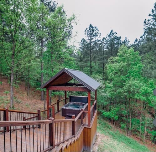 Hot tub on covered, extended wooden deck with forest view