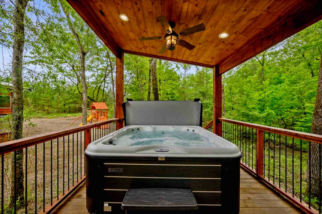 large hot tub on back wooden deck near creek