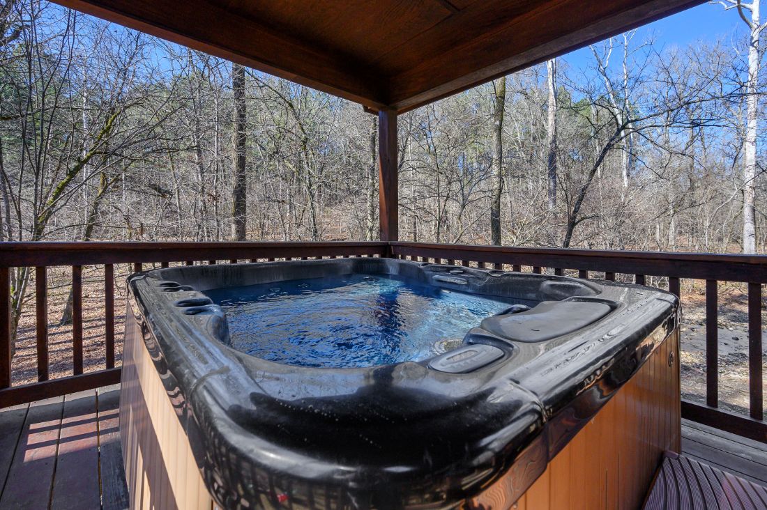 Hot tub under covered wooden porch with forest view
