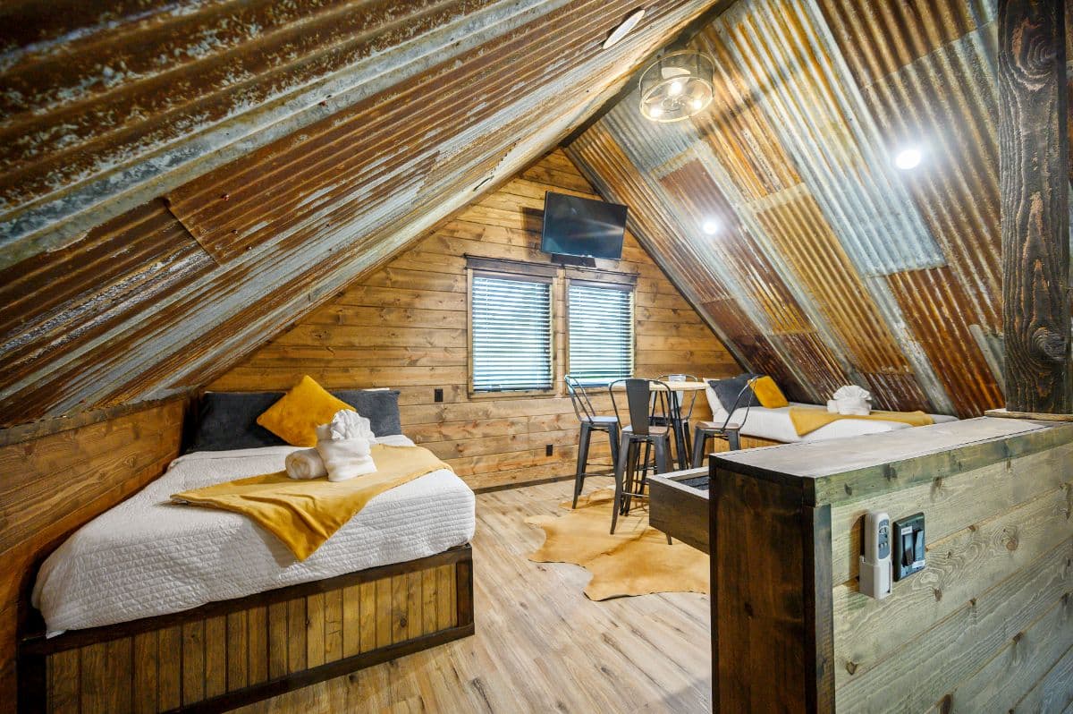 upstairs loft with twin beds, tables, and TV