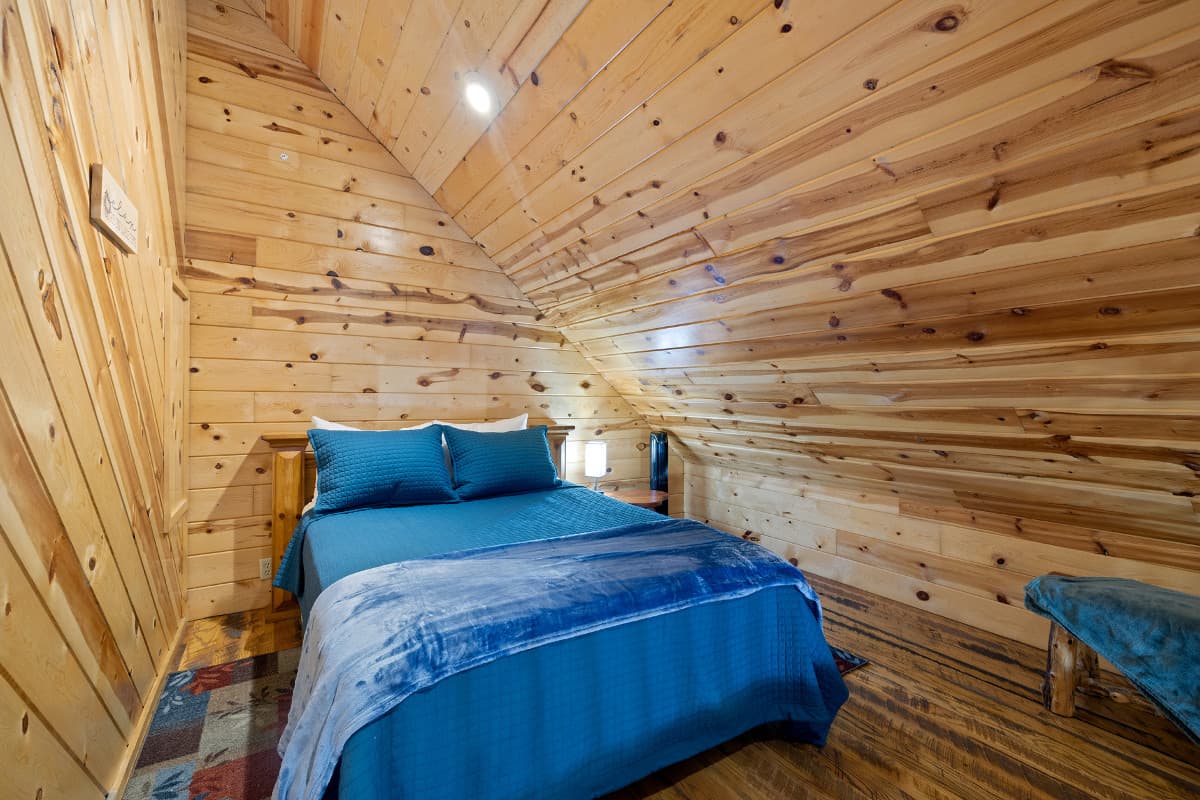 Upstairs loft bedroom with side table and lamp, bench