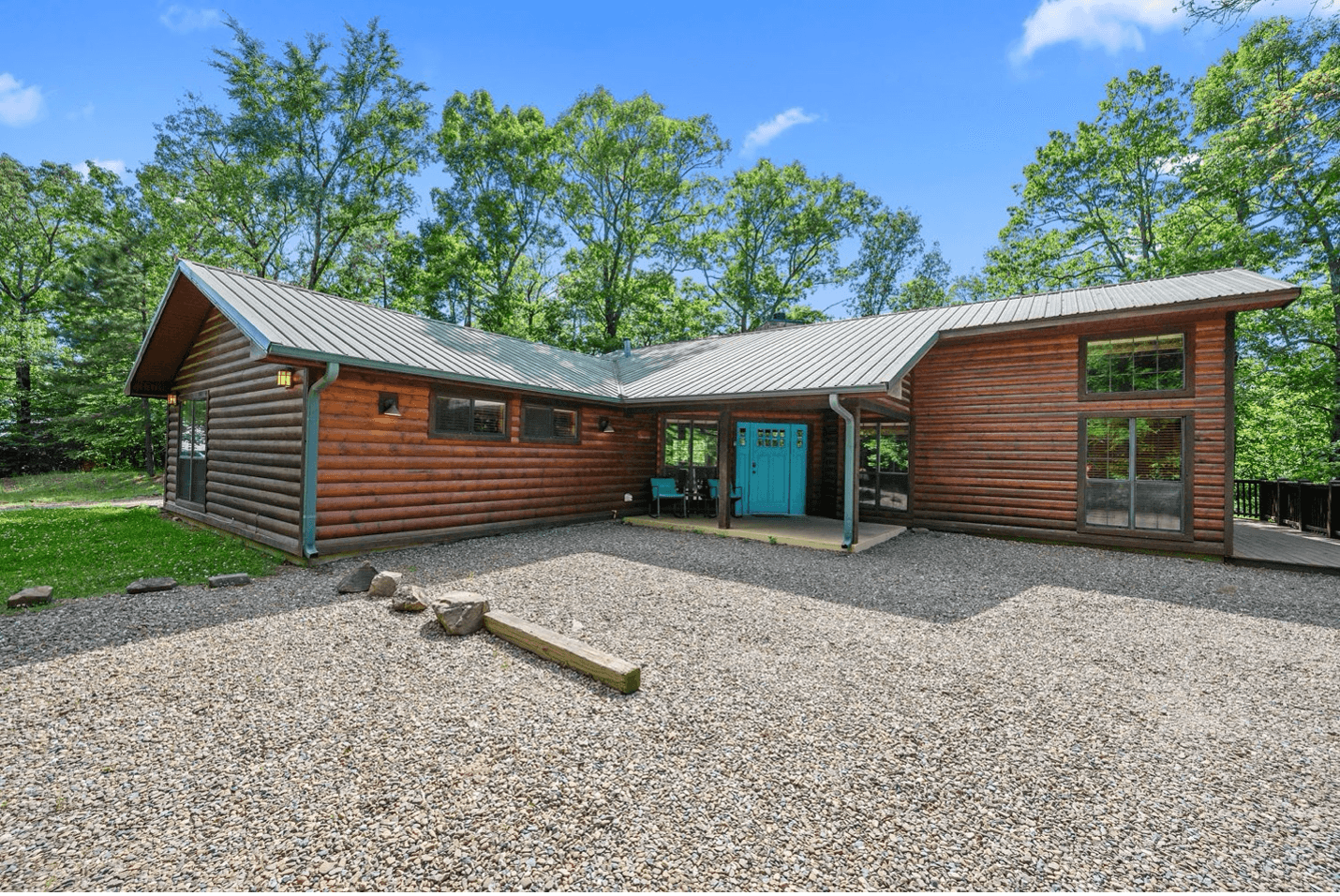 A wooden cabin with a satellite dish surrounded by trees and a playground on a sunny day.