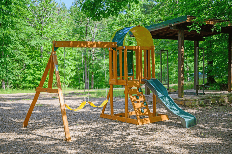 Cozy wooden cabin interior with a fireplace, leather sofas, and a ceiling fan.