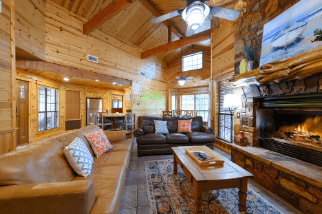Cozy wooden cabin interior with a fireplace, sofas, and rustic decor.