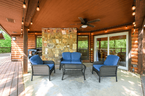 Exterior of a log cabin with a teal door, large windows, and surrounding greenery.