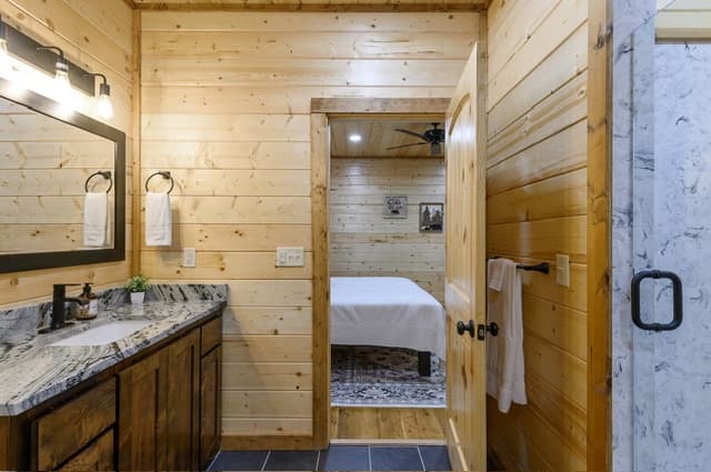 A cozy wooden cabin bathroom with a view into the adjoining bedroom.