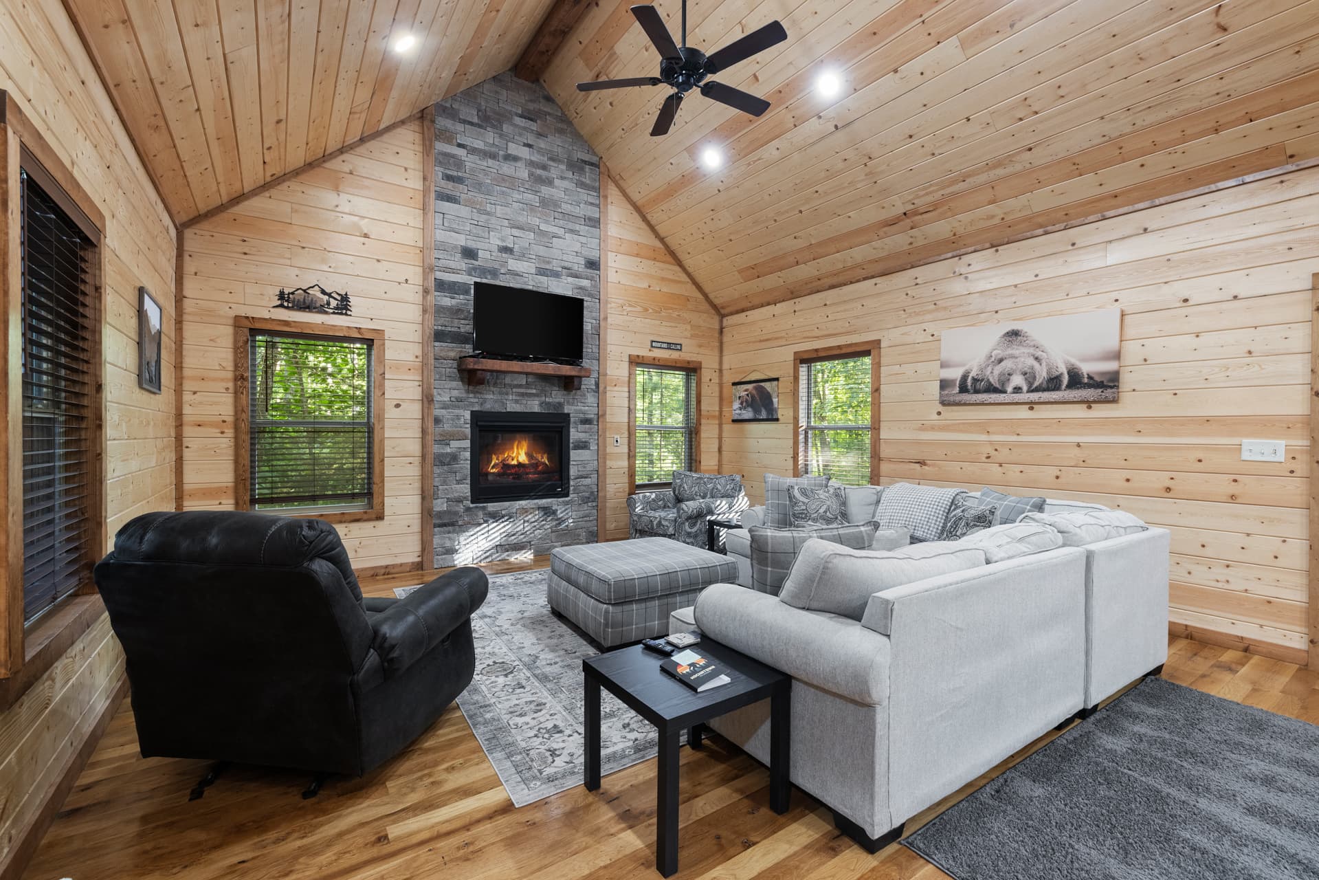 Cozy cabin living room with a fireplace, wooden walls, and comfortable sofas.