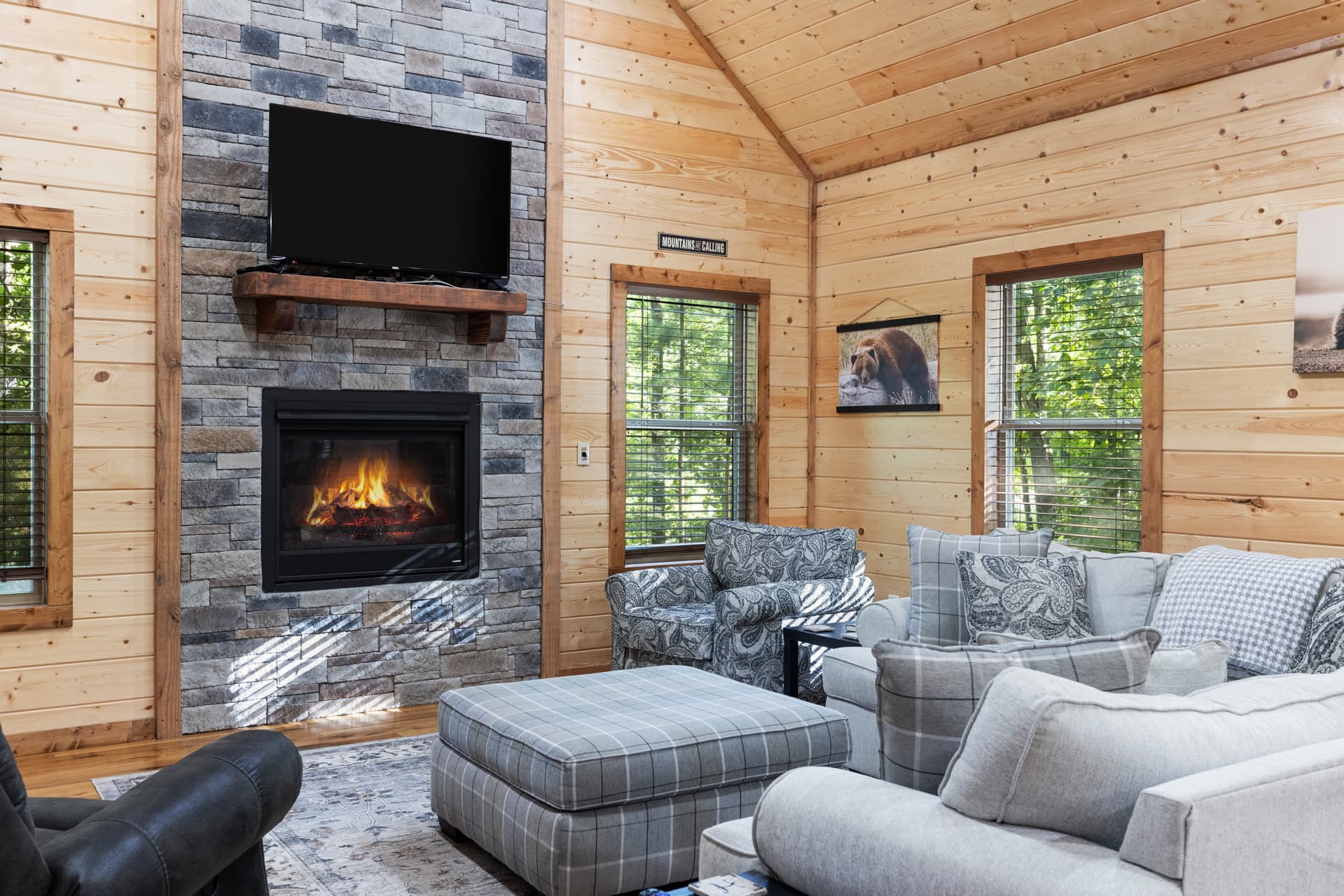 Cozy cabin living room with sectional sofa, armchairs, and wood-paneled walls.