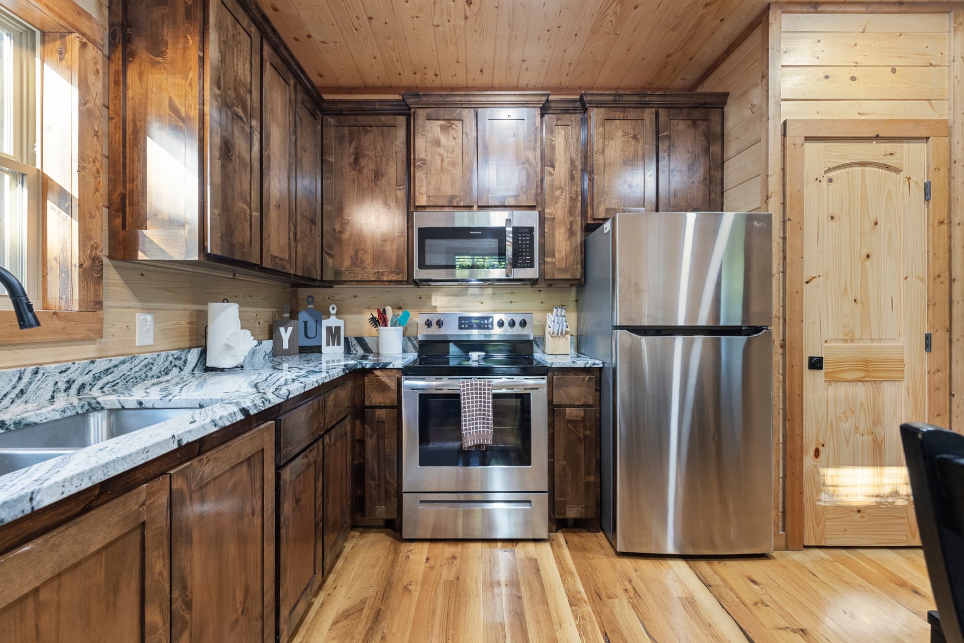 Cozy wooden cabin interior with plush sofas, a patterned rug, and kitchen in the background.