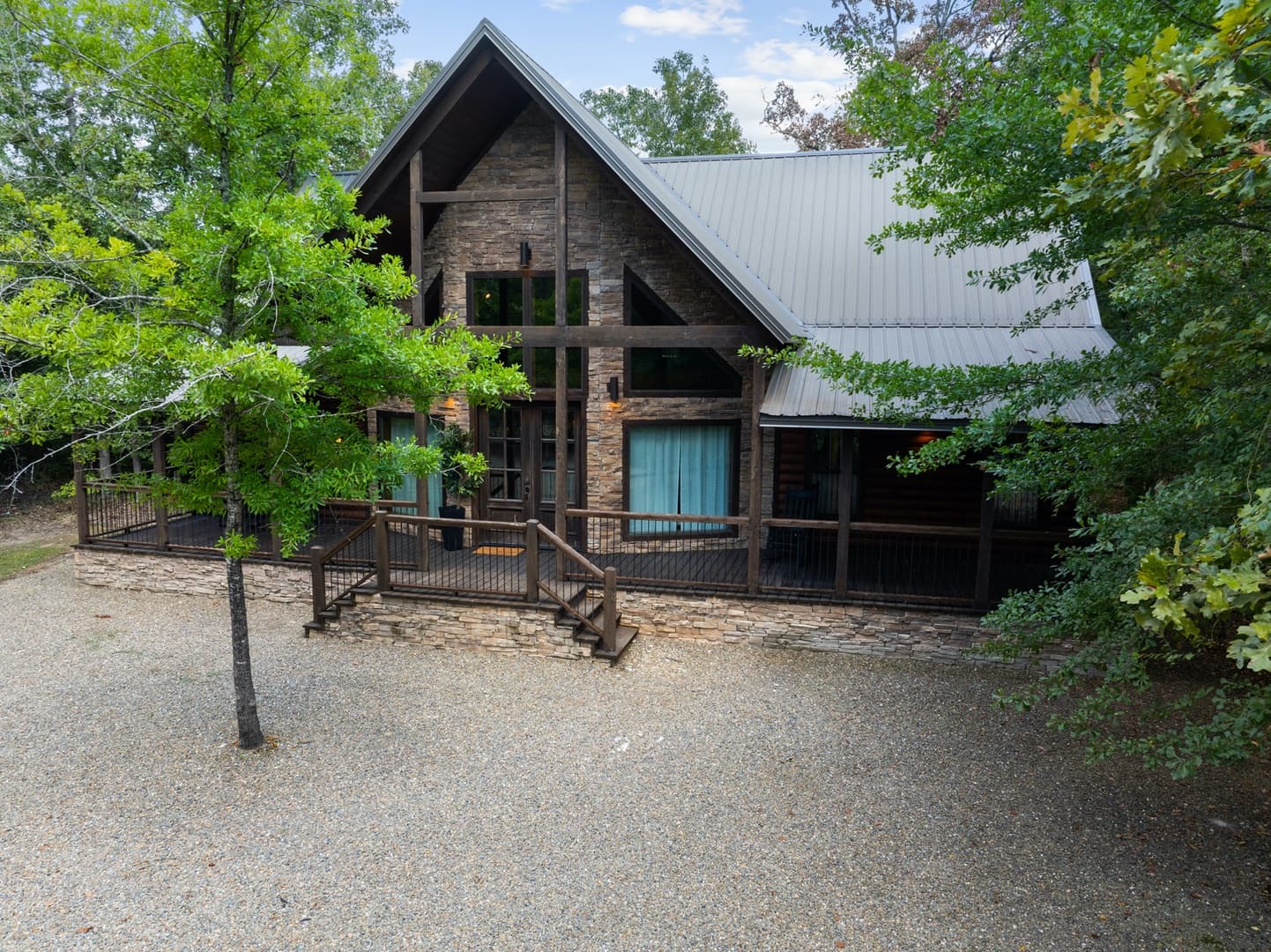 Rustic cabin with wooden and stone facade, surrounded by green trees.