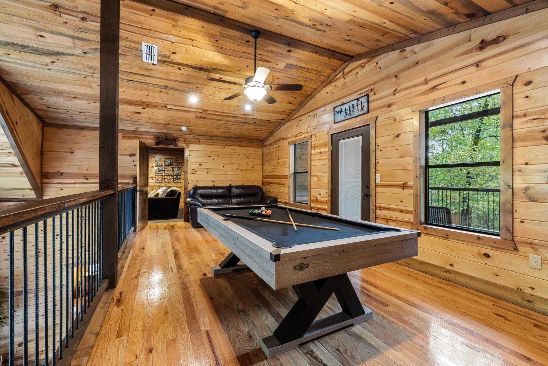 Rustic wooden cabin bedroom with a large bed, ceiling fan, and mounted TV.