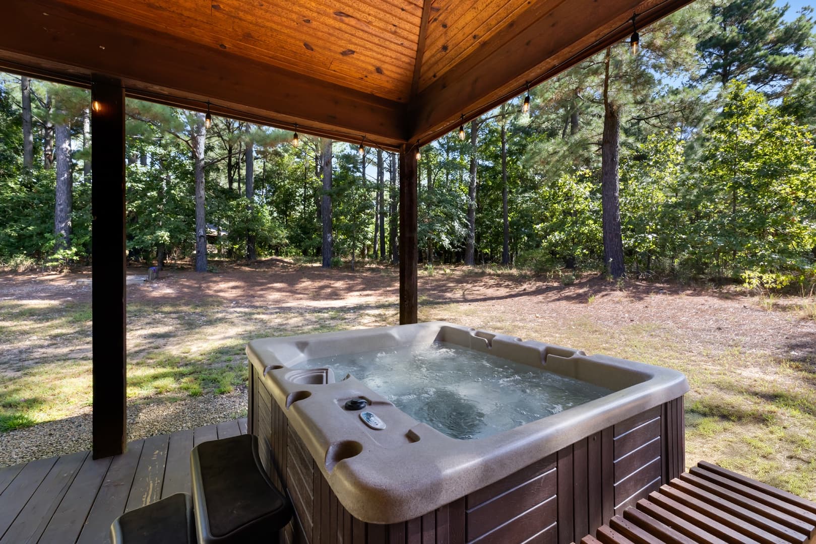 Hot tub under covered wooden porch with a nature view