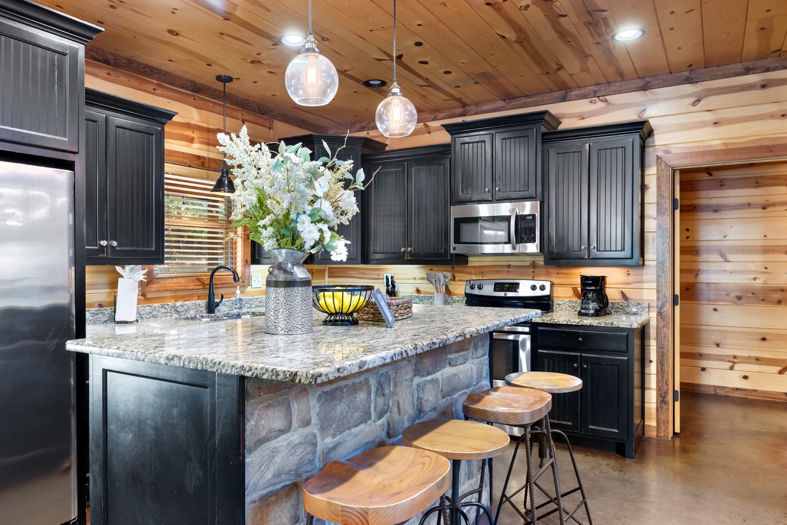An open kitchen with a bar and 4 stools