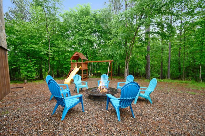 Campfire pit with blue chairs and a kids playground in background