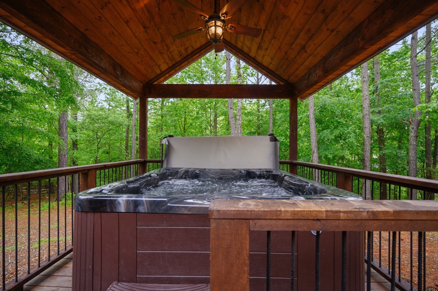 Hot tub under covered porch with forest view