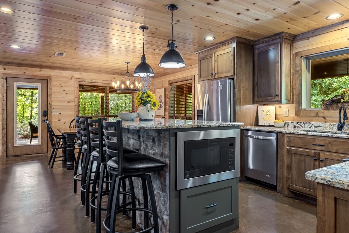 Open kitchen with stainless steel appliances, and an island with 4 stools