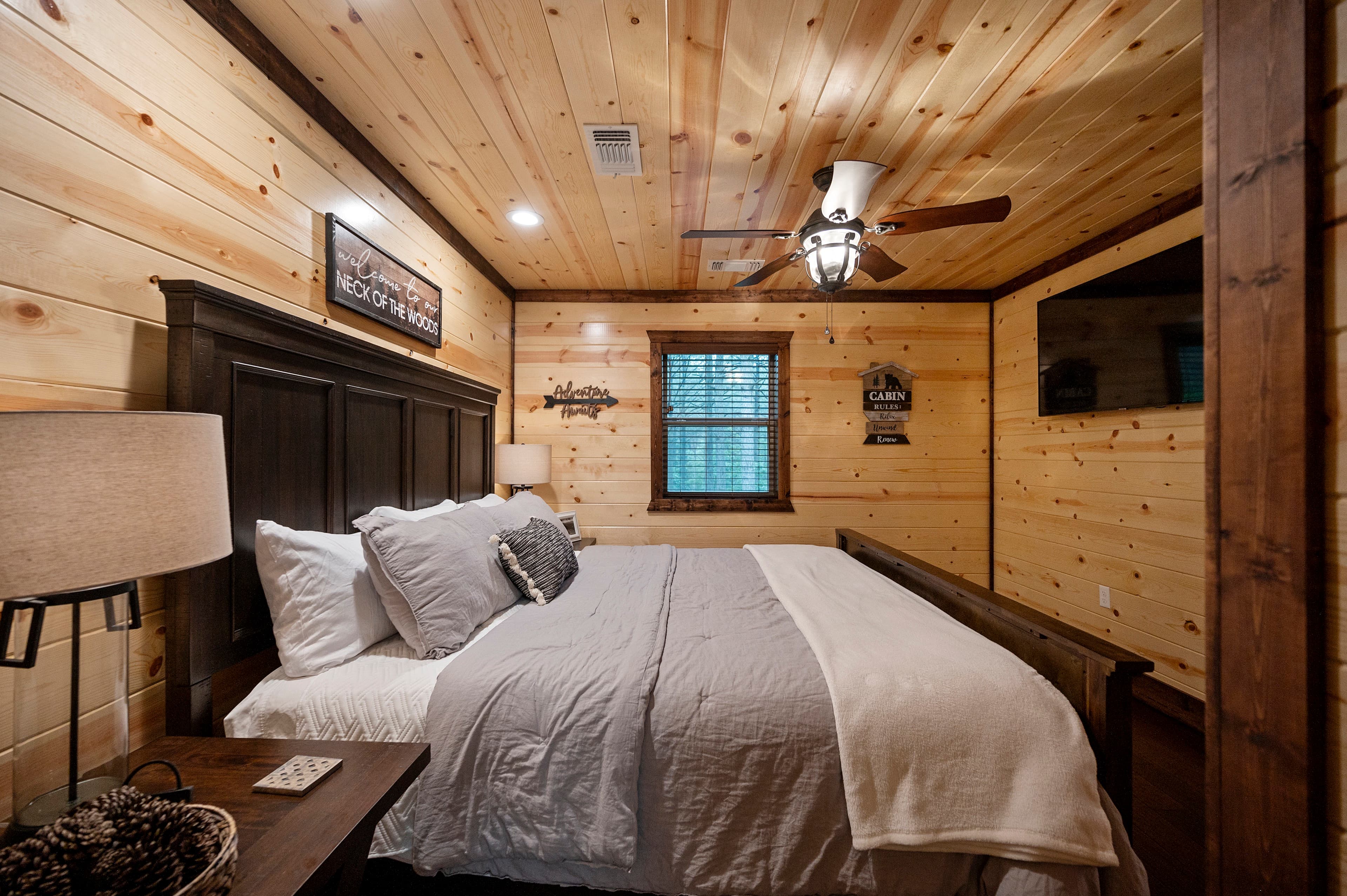 Cozy bedroom with wooden walls, a king-sized bed, and natural light from a window.