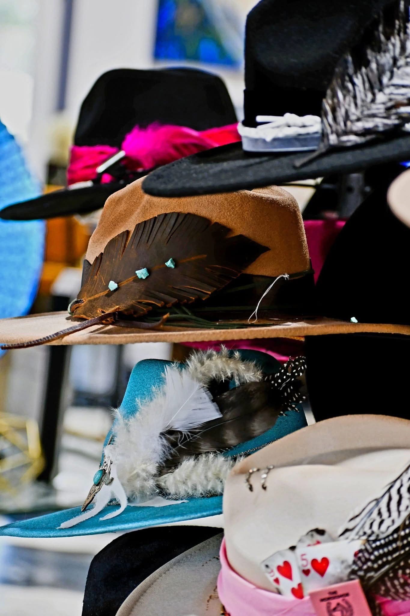 A collection of colorful hats displayed with various decorative elements, including feathers and beads.