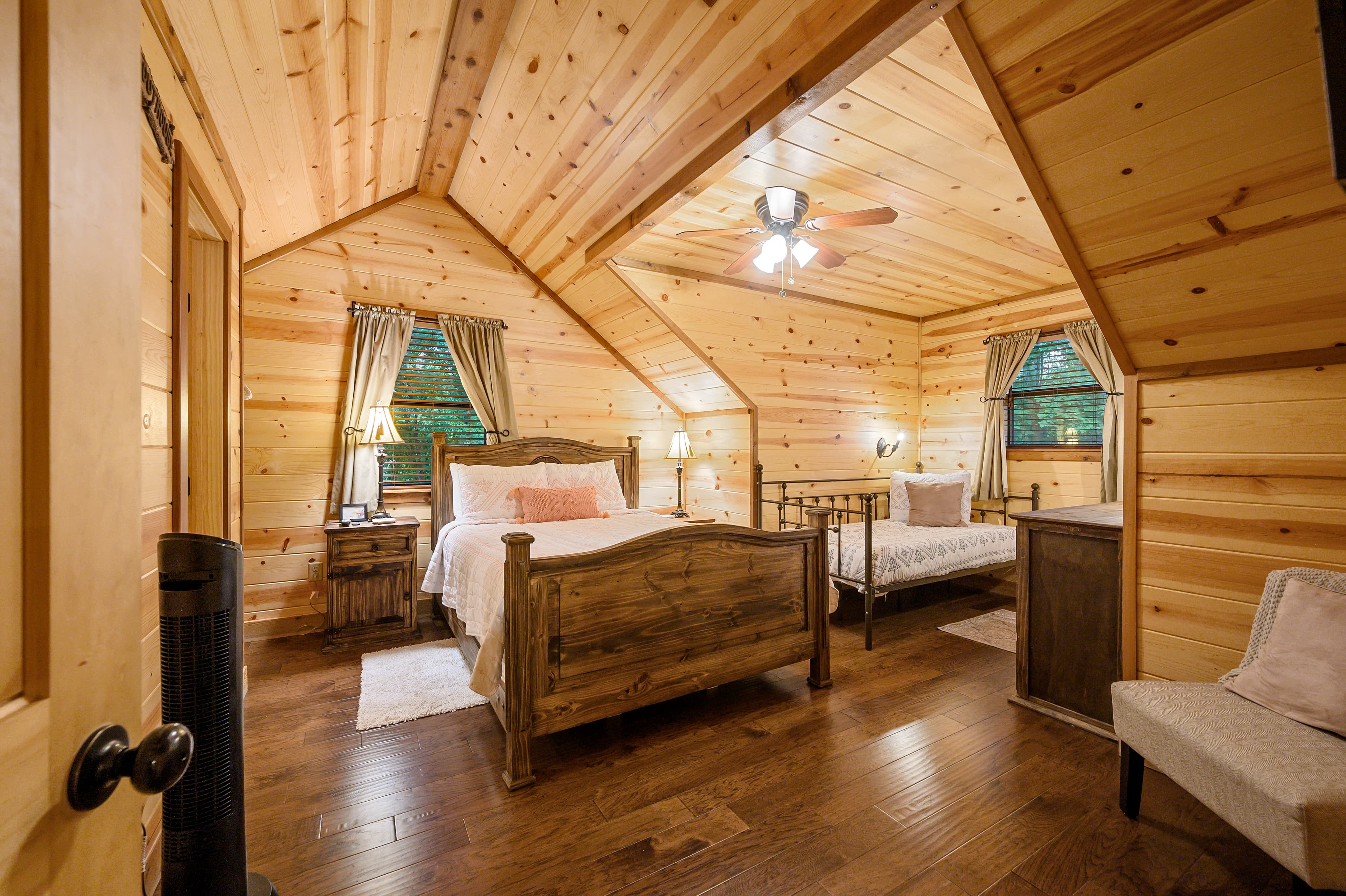 Cozy wood-paneled bedroom featuring a queen bed, twin bed, and rustic decor.