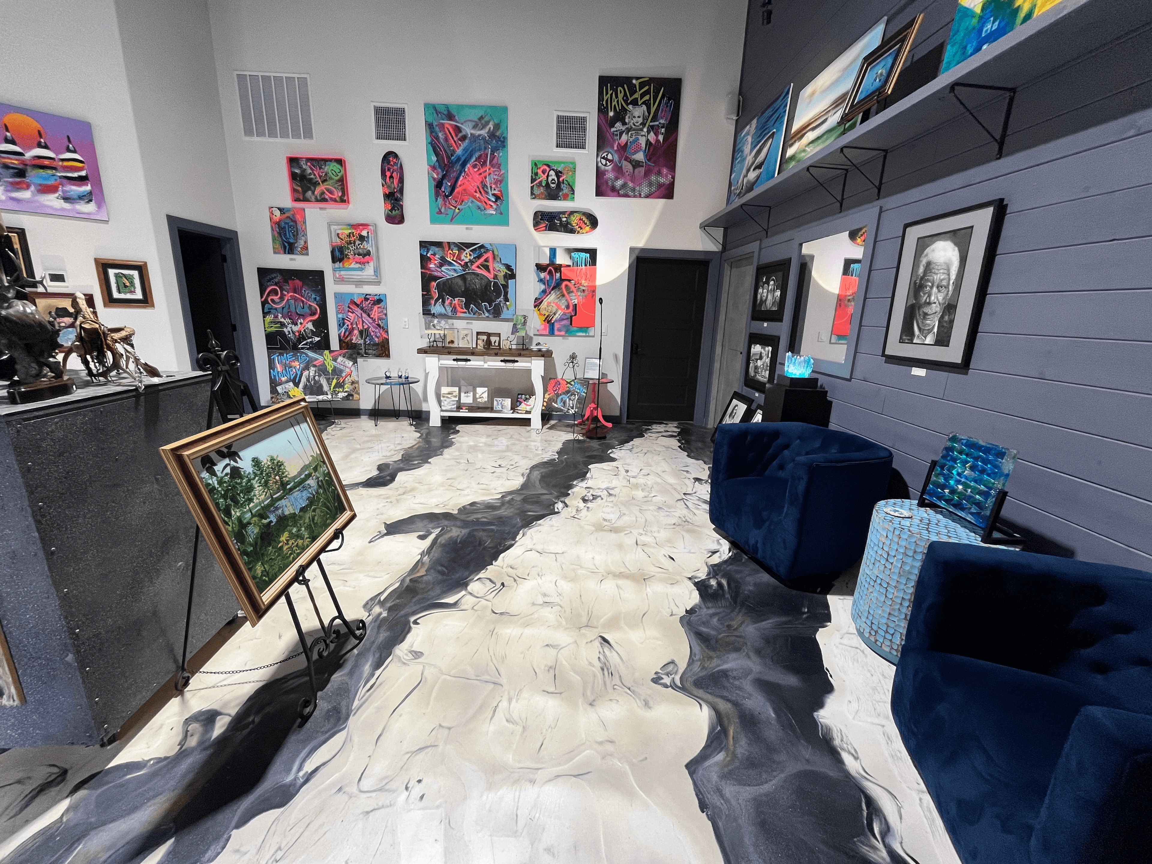 A brightly decorated art gallery featuring colorful paintings, sculptures, and a unique patterned floor.