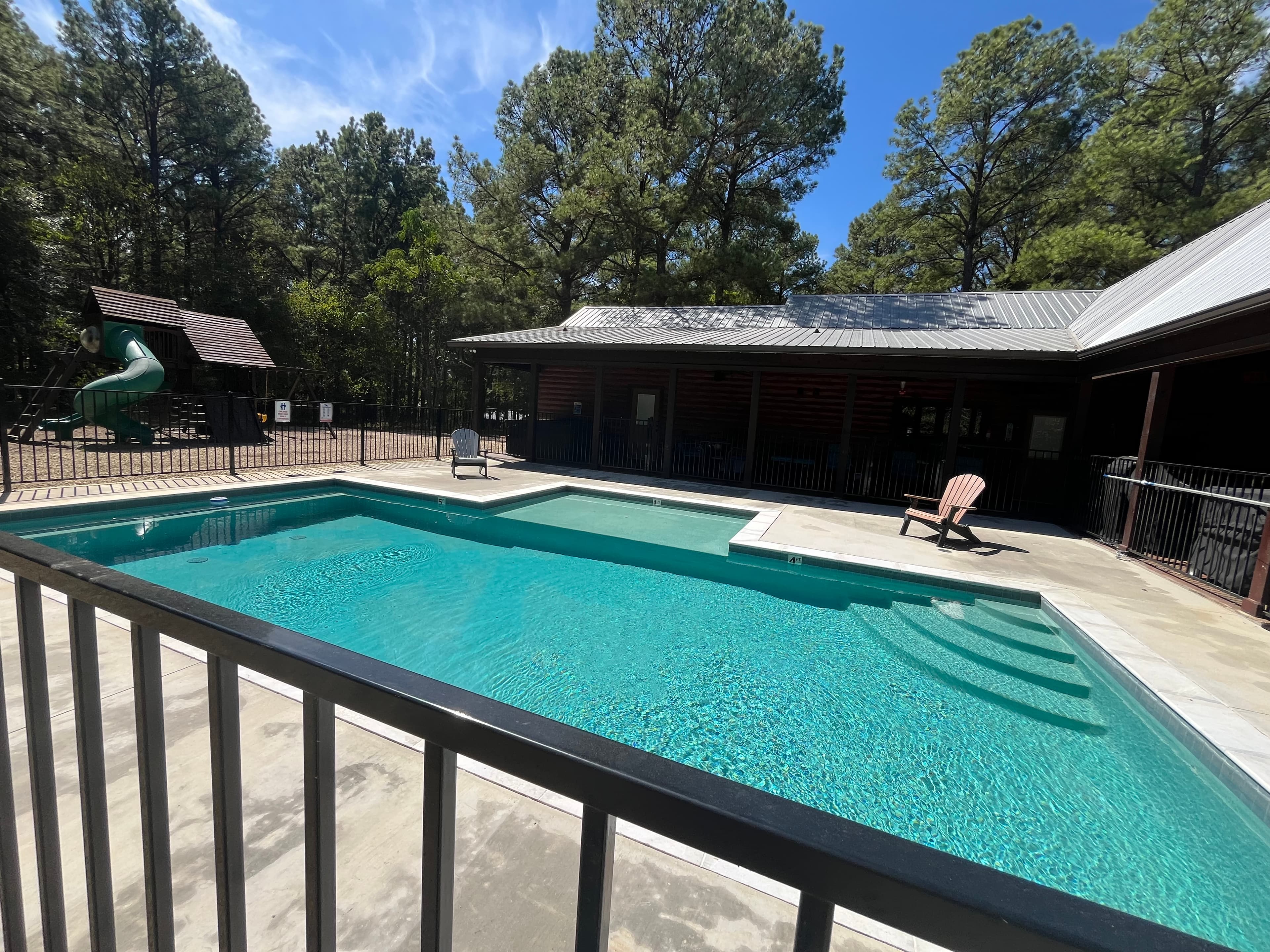 A sparkling pool surrounded by trees and a play area.
