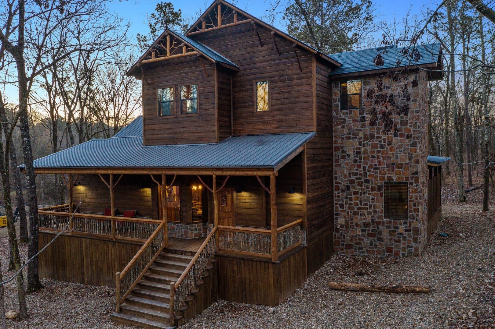 A rustic wooden house with a stone accent wall, surrounded by trees at dusk. A rustic wooden house with a stone accent wall, surrounded by trees at dusk.