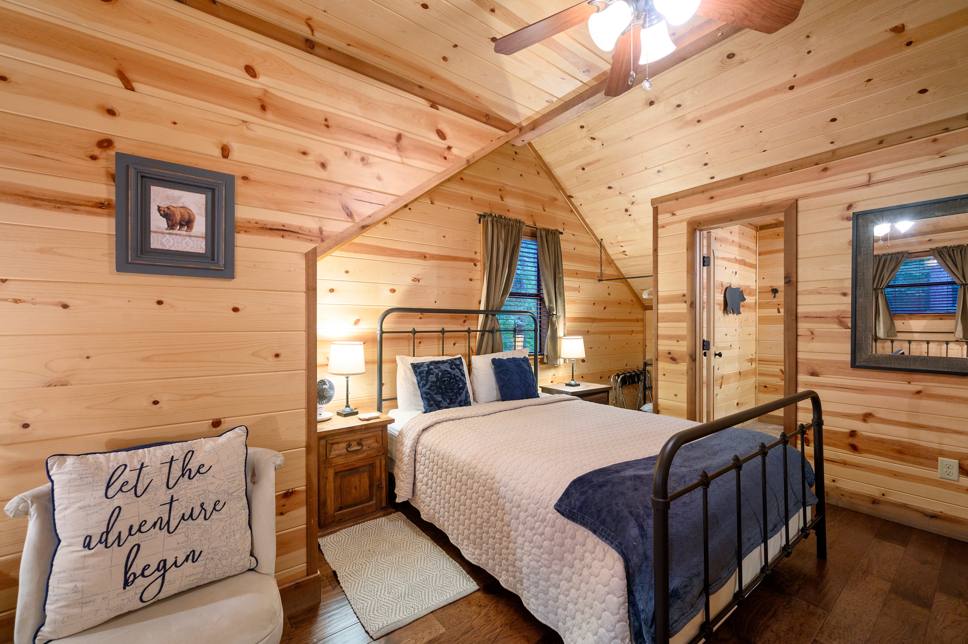 A cozy wooden bedroom with a metal bed frame, decorative pillows, and a motivational throw pillow.