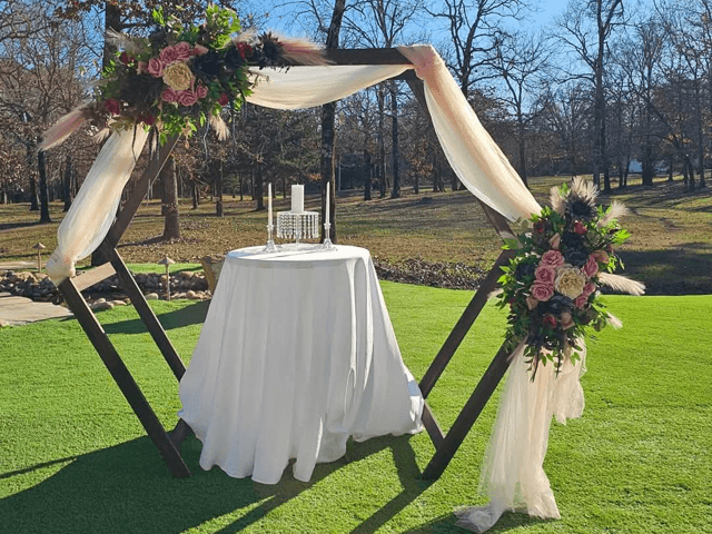 An elegantly decorated outdoor altar with floral arrangements and a table set for a ceremony.