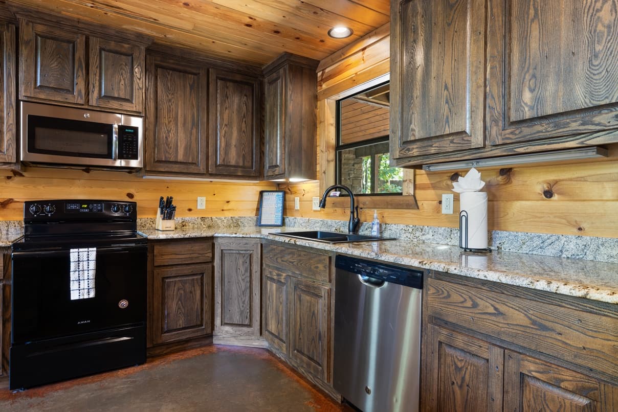 Rustic kitchen with dark wood cabinets, stainless steel appliances, and granite countertops.