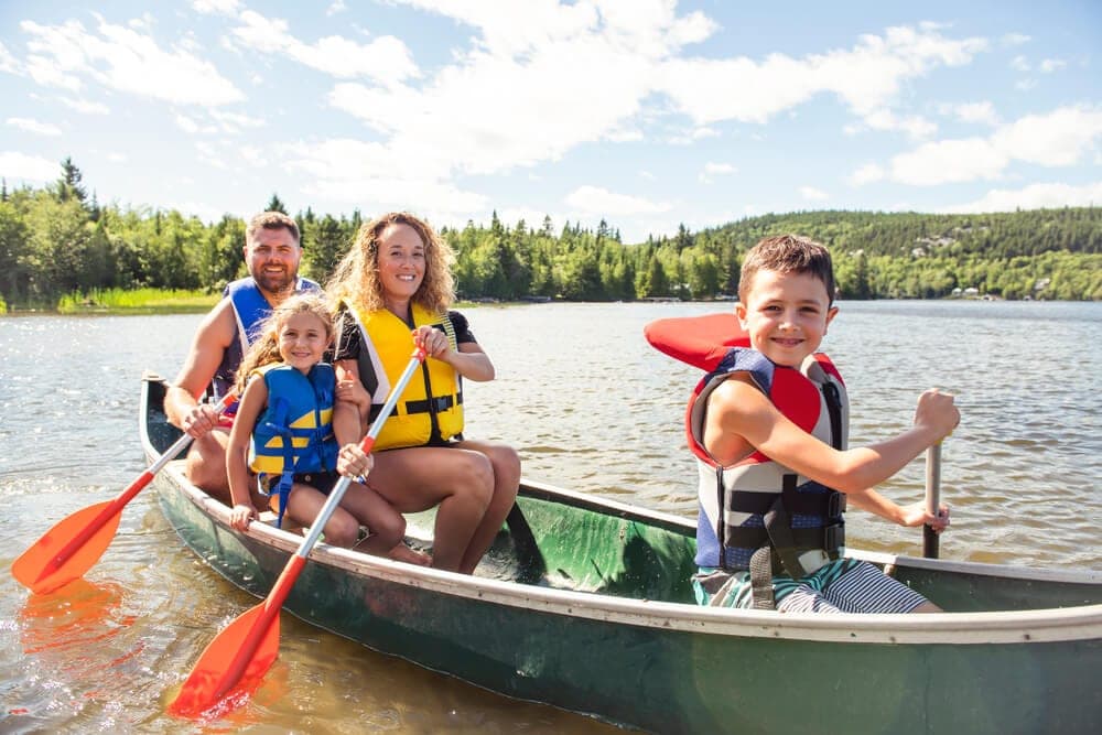 A family of four enjoys canoeing on a sunny lake.