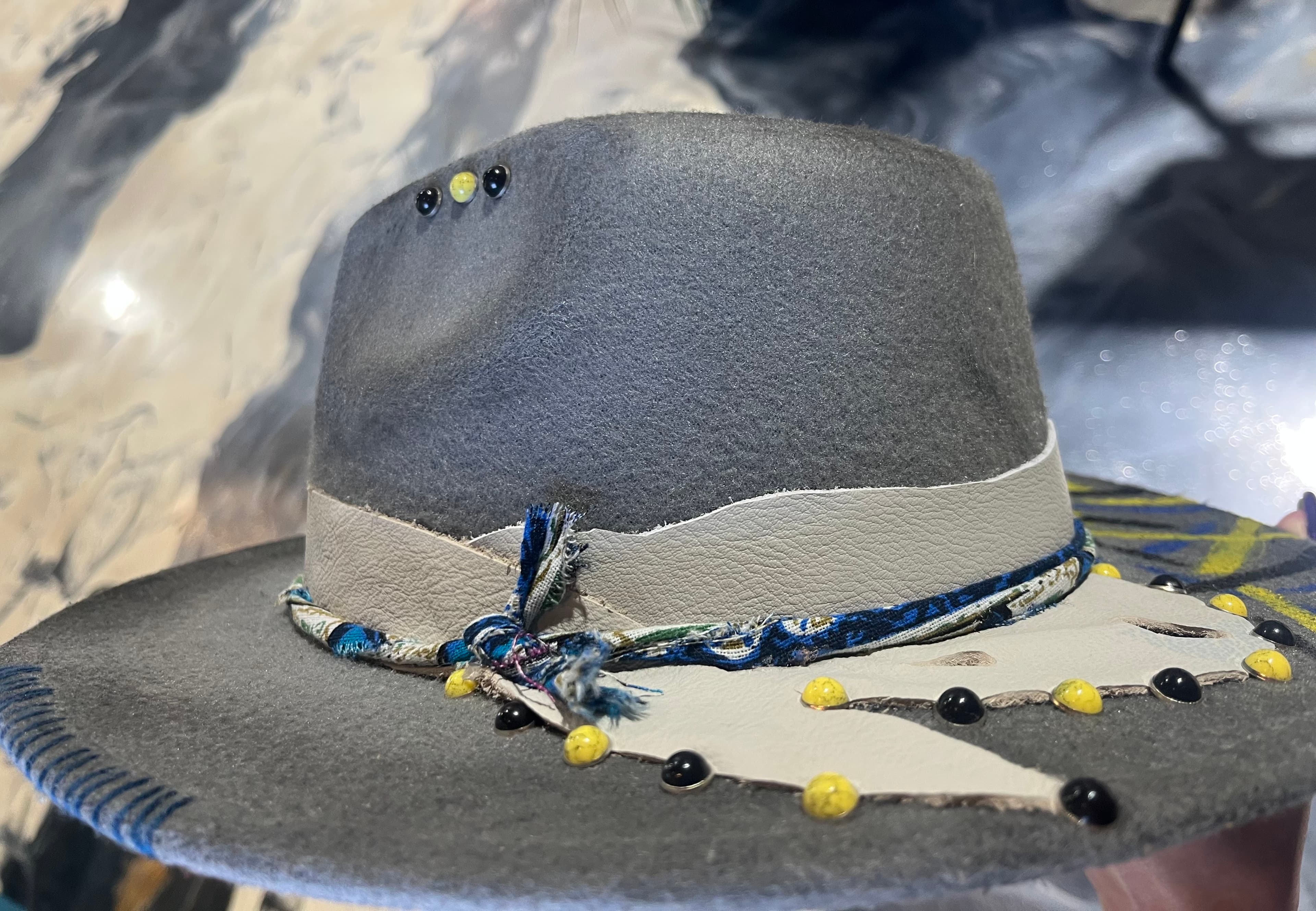 A gray hat adorned with colorful beads and a decorative band.