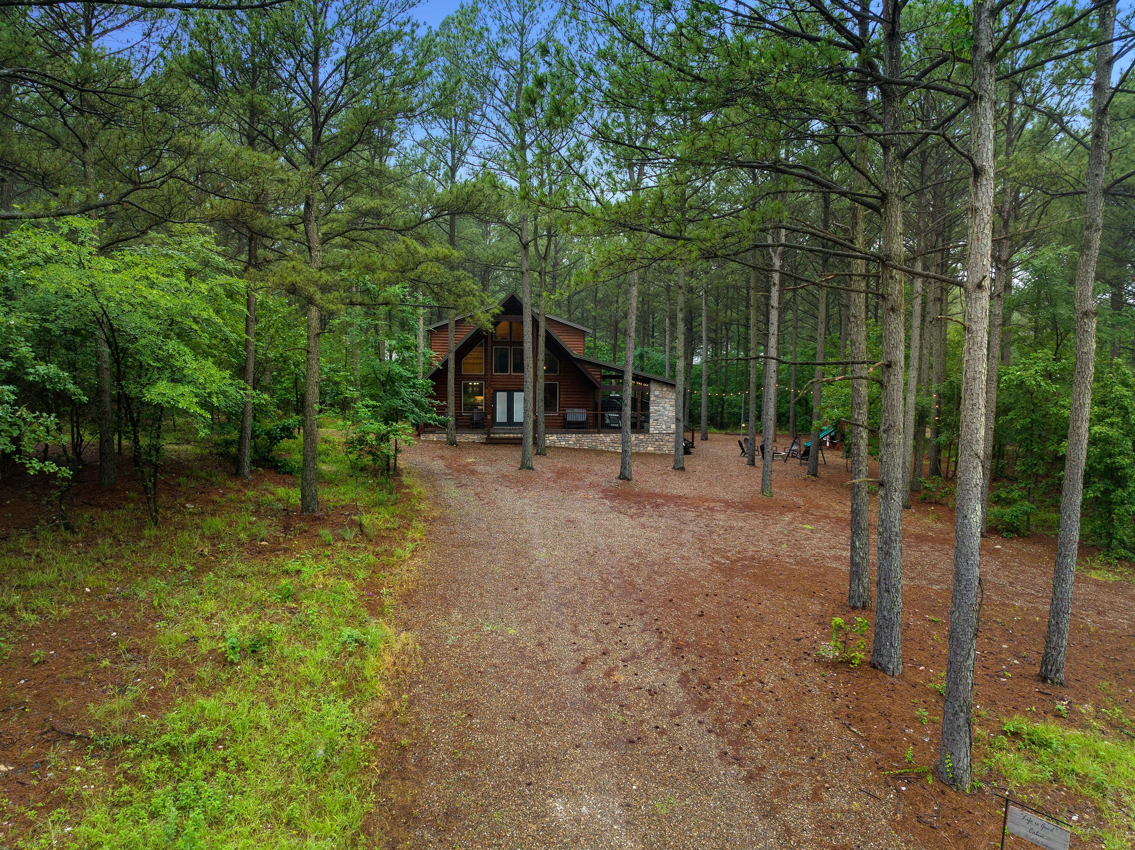 A cabin nestled among tall pine trees on a gravel path.