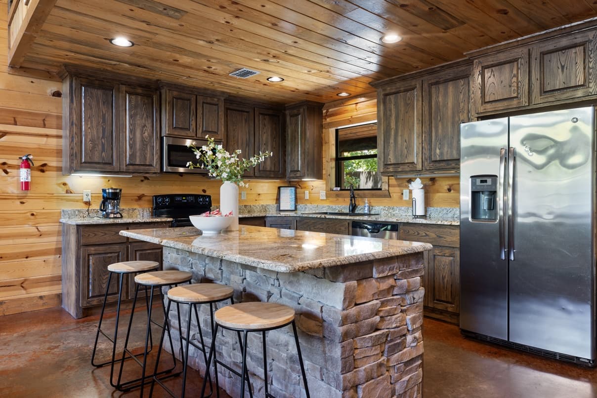 Rustic kitchen with wood paneling, stone island, and modern appliances.